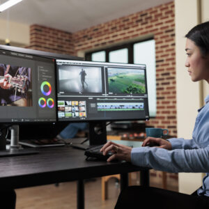 How to Include Video in Your Marketing Strategy? 4 Asian professional video editor sitting at multi monitor workspace while enhancing movie footage quality using advanced software. Post production house team leader editing film frames.
